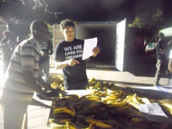 Artist Jean-François Boclé setting up his installation made of bananas at night. He wears the exhibition T-shirt